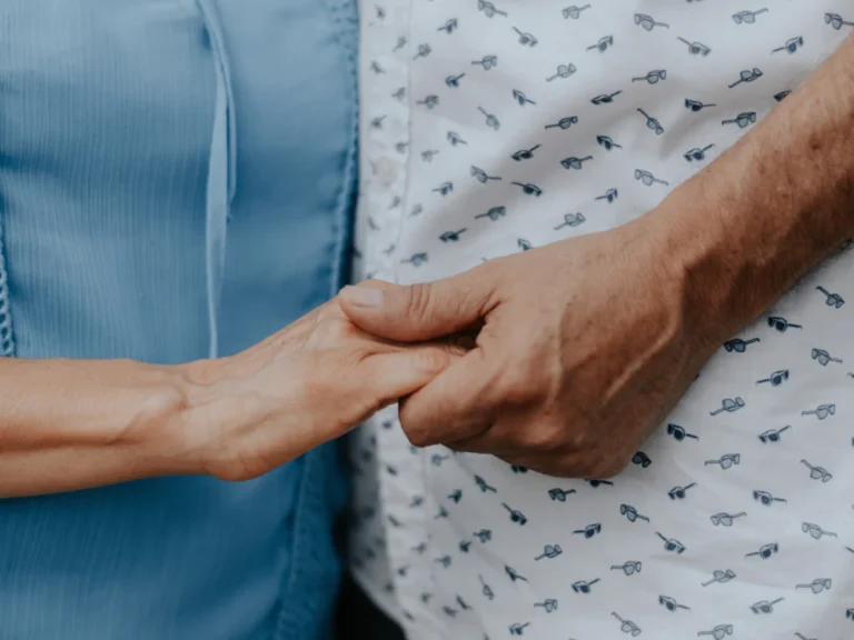 Main d’une accompagnante tenant celle d’une patiente âgée