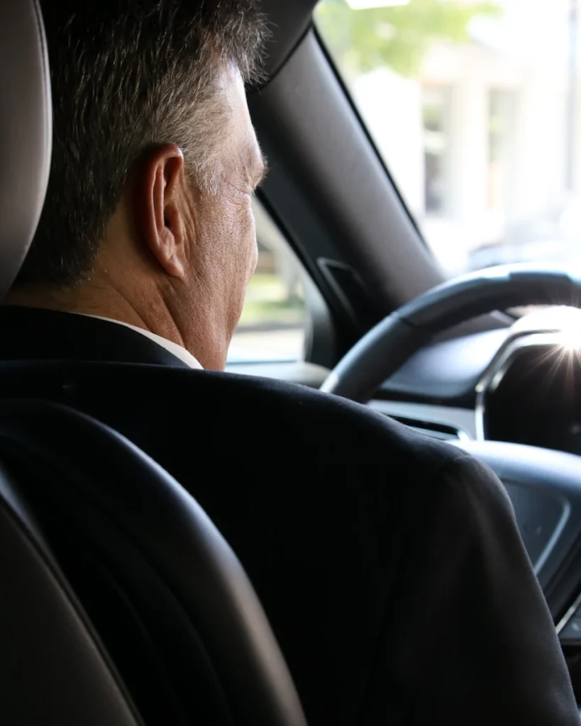 Chauffeur en tenue sombre au volant, prêt à prendre la route
